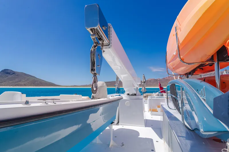 Huracan Yacht Photos Pics Delta Marine Expedition yacht deck with kayaks, blue sea, and mountainous backdrop, 1991 model.