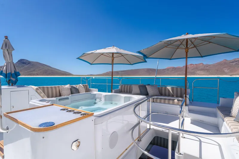 Huracan Yacht Photos Pics Luxurious 1991 Delta Marine Expedition yacht deck with hot tub, umbrellas, and ocean view.