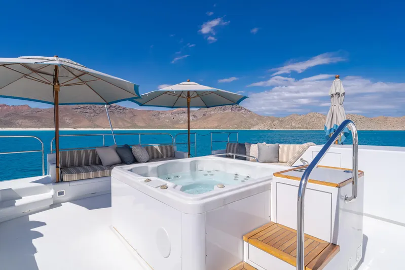 Huracan Yacht Photos Pics Luxurious Delta Marine Expedition yacht deck with hot tub, umbrellas, and scenic ocean view.