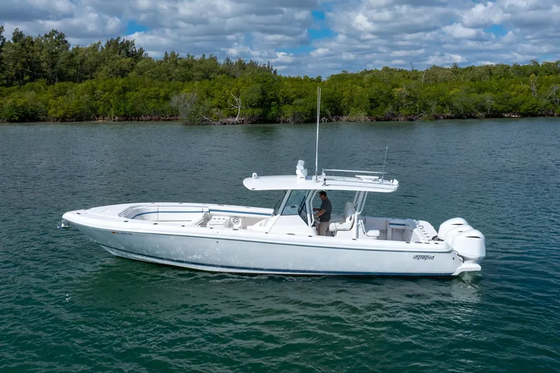  Yacht Photos Pics 2017 Intrepid 375 Center Console boat on calm water, surrounded by lush greenery.