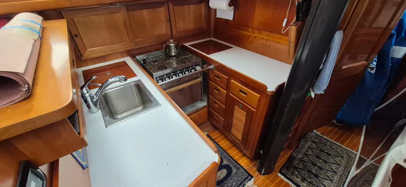 Blue Skies Yacht Photos Pics Interior of 1990 Able Chuck Paine Sloop, featuring a compact kitchen with sink and stove.