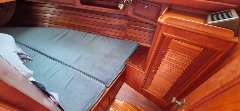 Blue Skies Yacht Photos Pics Interior of 1990 Able Chuck Paine Sloop with wooden cabinetry and cushioned berth.