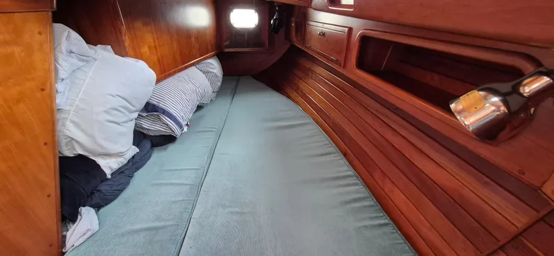 Blue Skies Yacht Photos Pics Cozy cabin interior of 1990 Able Chuck Paine Sloop with wooden finish and bedding.