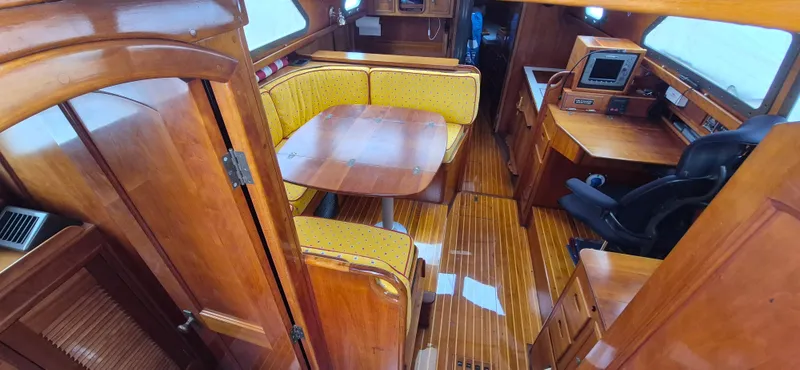 Blue Skies Yacht Photos Pics Interior of 1990 Able Chuck Paine Sloop with wooden furnishings and yellow cushioned seating.