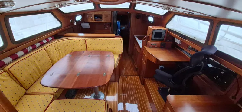 Blue Skies Yacht Photos Pics Interior of 1990 Able Chuck Paine Sloop with wooden furnishings and yellow seating.
