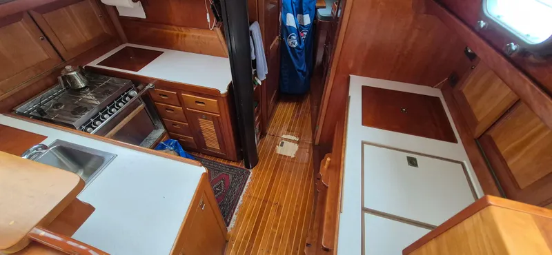 Blue Skies Yacht Photos Pics Interior of 1990 Able Chuck Paine Sloop with wooden cabinetry and compact kitchen area.
