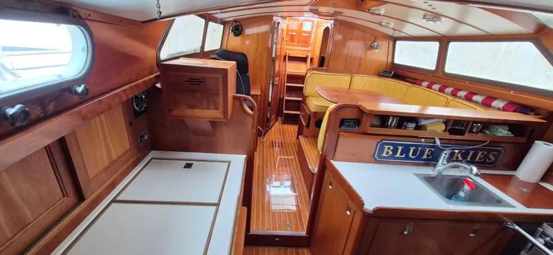Blue Skies Yacht Photos Pics Interior of 1990 Able Chuck Paine Sloop with wooden finish and cozy seating area.