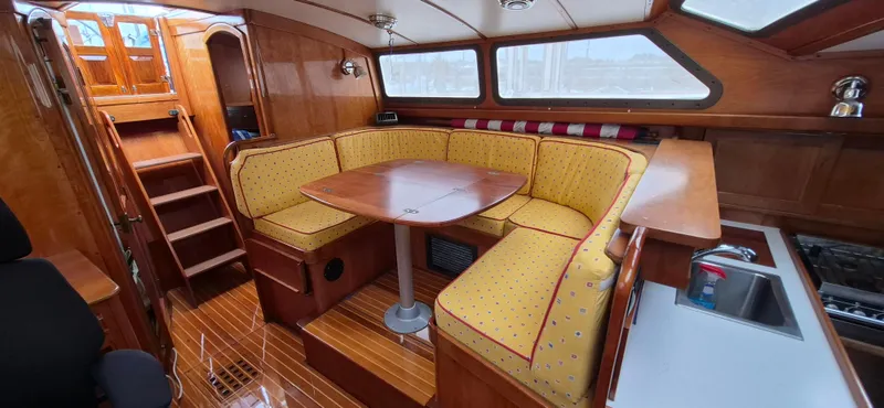 Blue Skies Yacht Photos Pics Interior of a 1990 Able Chuck Paine Sloop with wooden finishes and yellow seating.