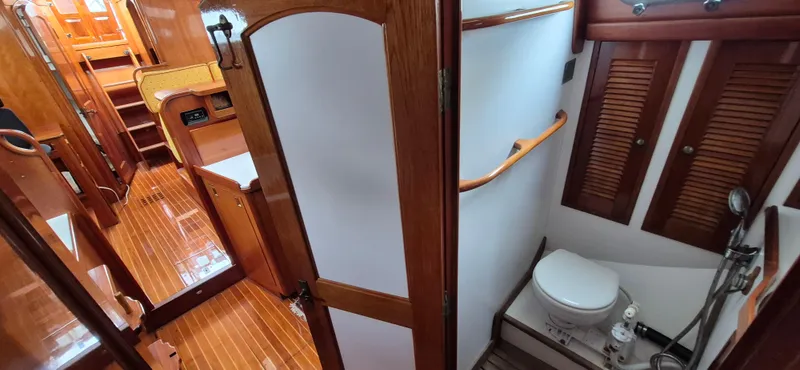Blue Skies Yacht Photos Pics Interior of 1990 Able Chuck Paine Sloop with wooden finishes and compact bathroom.