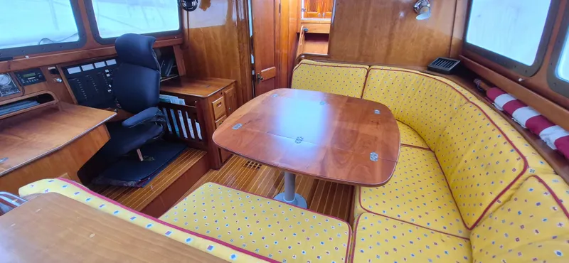 Blue Skies Yacht Photos Pics Cozy interior of 1990 Able Chuck Paine Sloop with yellow cushioned seating and wooden table.