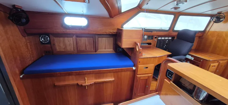 Blue Skies Yacht Photos Pics Interior of a 1990 Able Chuck Paine Sloop with wooden furnishings and blue seating.