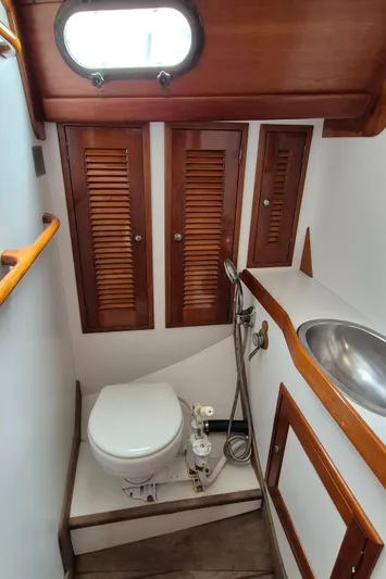 Blue Skies Yacht Photos Pics 1990 Able Chuck Paine Sloop bathroom with wooden cabinets and compact marine toilet.