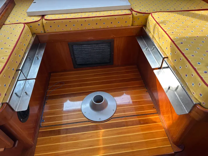 Blue Skies Yacht Photos Pics Interior of 1990 Able Chuck Paine Sloop with yellow cushioned seating and wooden flooring.