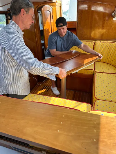 Blue Skies Yacht Photos Pics Two people adjusting a table inside a 1990 Able Chuck Paine Sloop yacht.