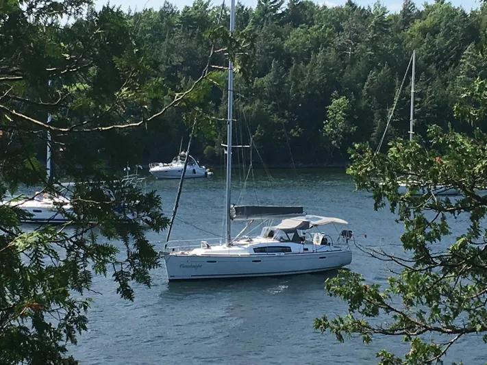 Farenheight Yacht Photos Pics Sailboat Beneteau Oceanis 40, 2008 model, anchored in a serene, tree-lined lake.