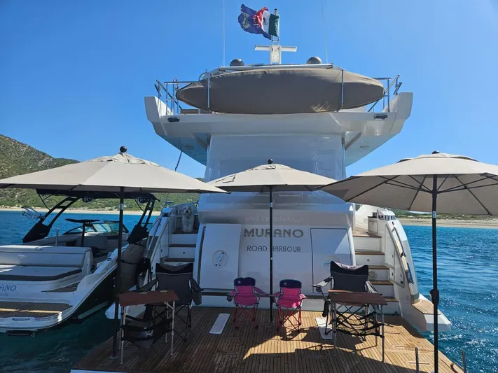 Murano Yacht Photos Pics Azimut 72 FLY 2018 yacht with deck chairs and umbrellas, anchored in scenic waters.