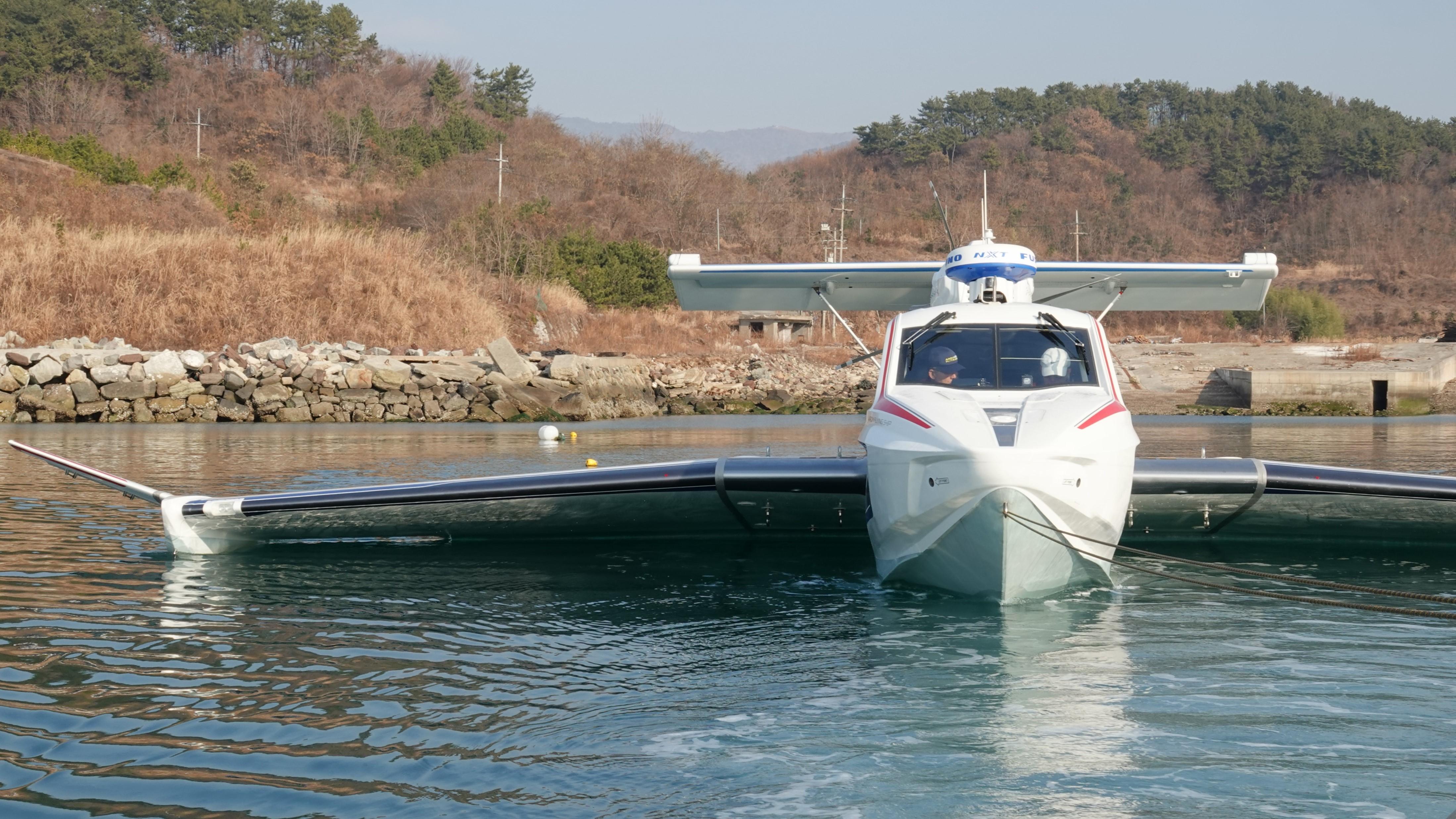 Futuristic Aron M 80 seaplane on water, surrounded by scenic landscape, 2025 model.