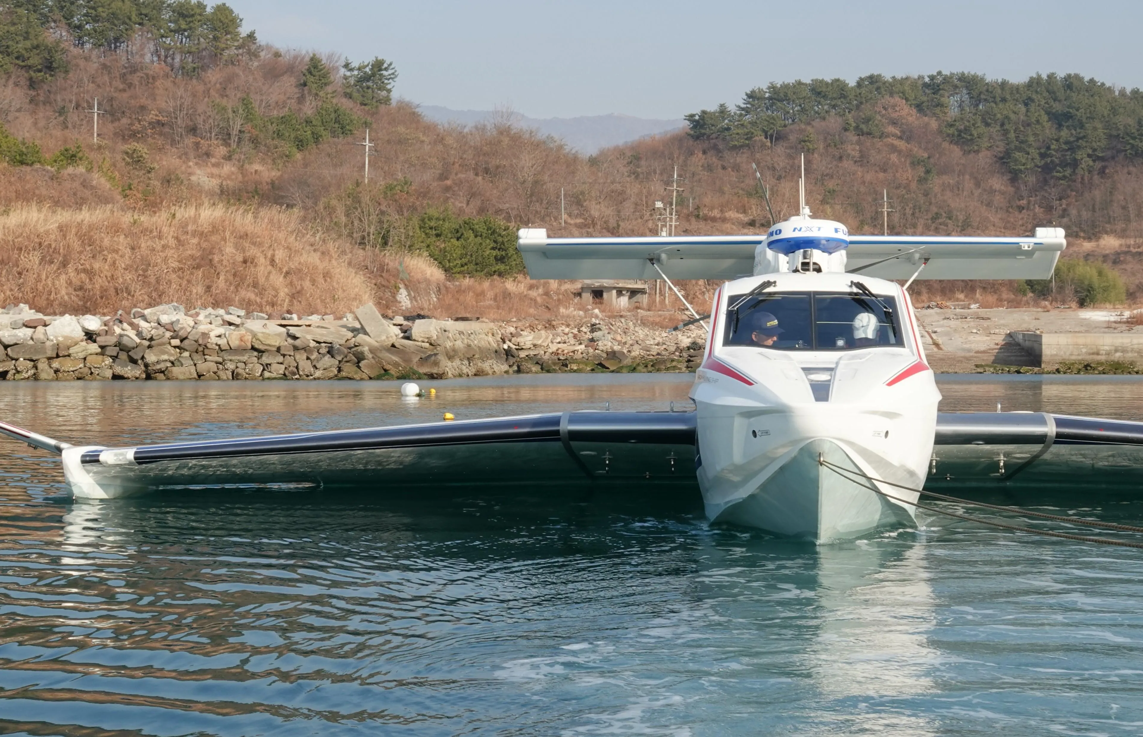 Futuristic Aron M 80 seaplane on water, surrounded by scenic landscape, 2025 model.