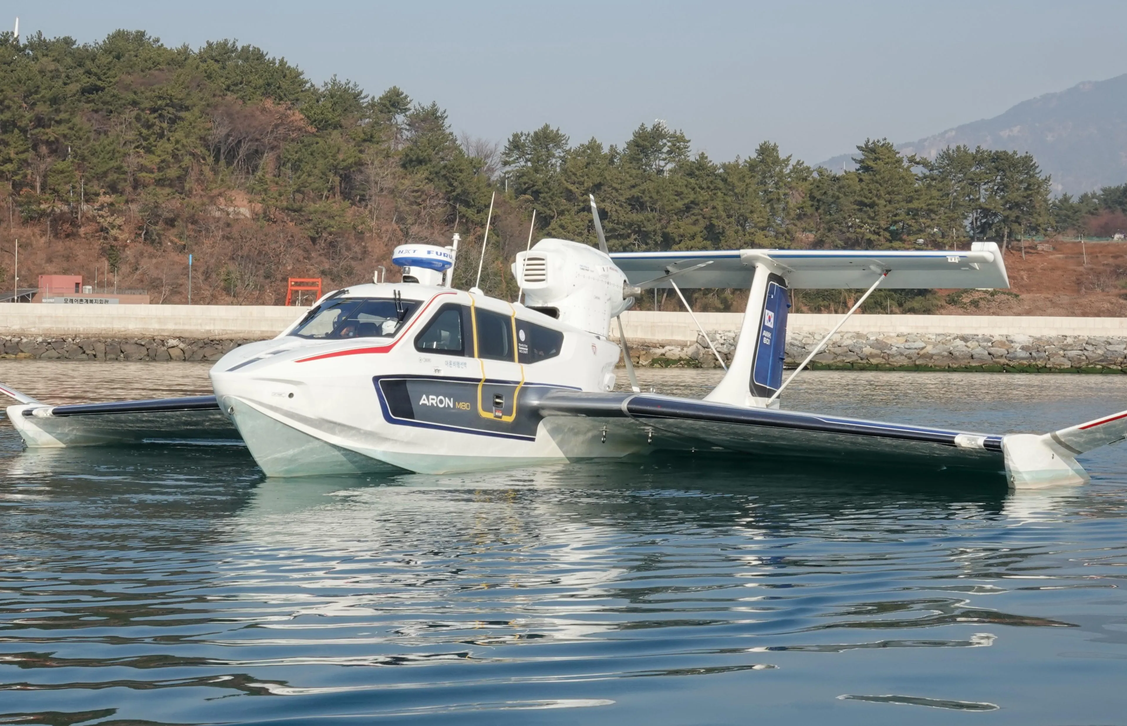 2025 Aron M 80 seaplane on calm water, surrounded by trees and mountains.