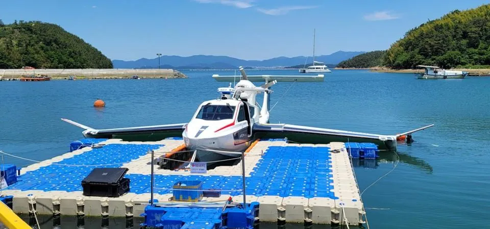 Seaplane Aron M 80 (2025) docked on a floating platform in a scenic harbor.