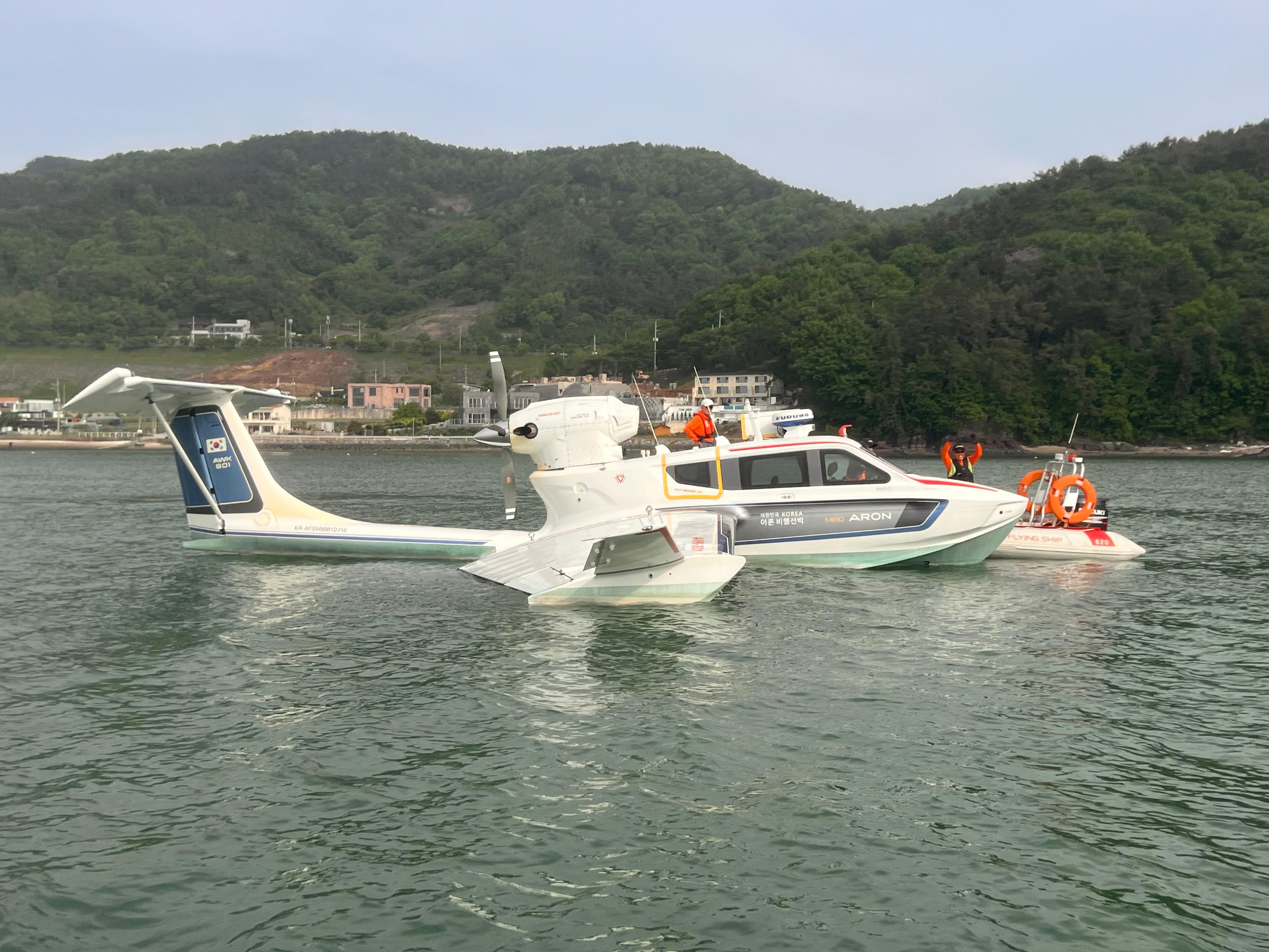 Futuristic Aron M 80 seaplane on water, 2025 model, with scenic mountain backdrop.