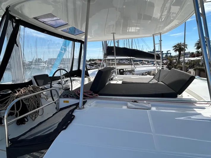  Yacht Photos Pics 2024 Lagoon 46 yacht deck with seating, marina view, and clear skies.
