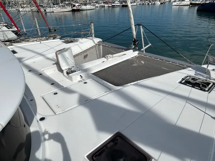  Yacht Photos Pics 2024 Lagoon 46 catamaran deck with netting, docked in a marina.