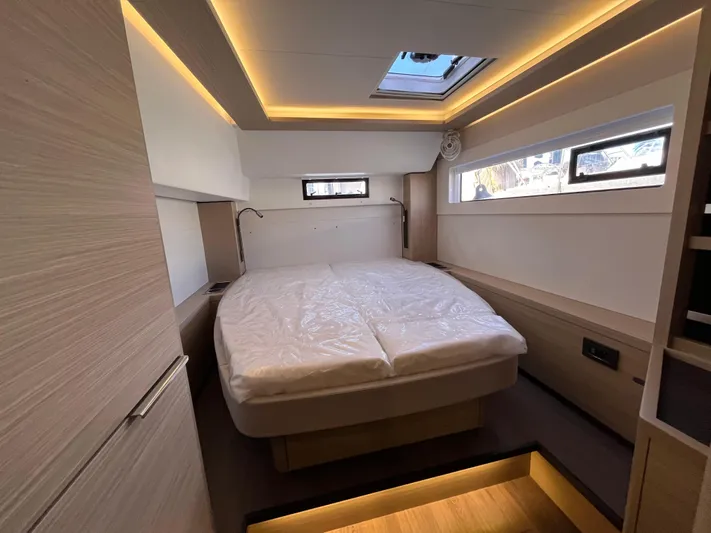  Yacht Photos Pics 2024 Lagoon 46 yacht cabin with modern design, featuring a cozy bed and ambient lighting.