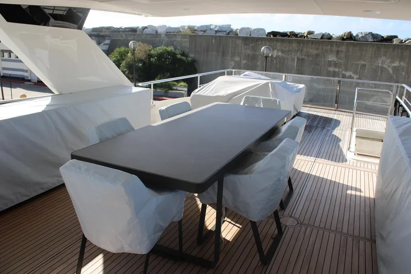  Yacht Photos Pics Outdoor dining area on 2025 Absolute NAVETTA 70 yacht with covered chairs and table.