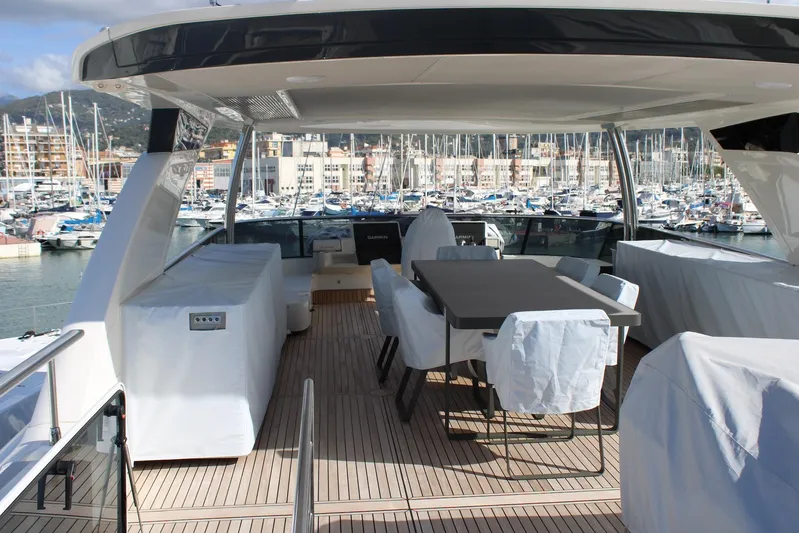  Yacht Photos Pics Luxurious 2025 Absolute NAVETTA 70 yacht deck with covered seating, docked at a marina.