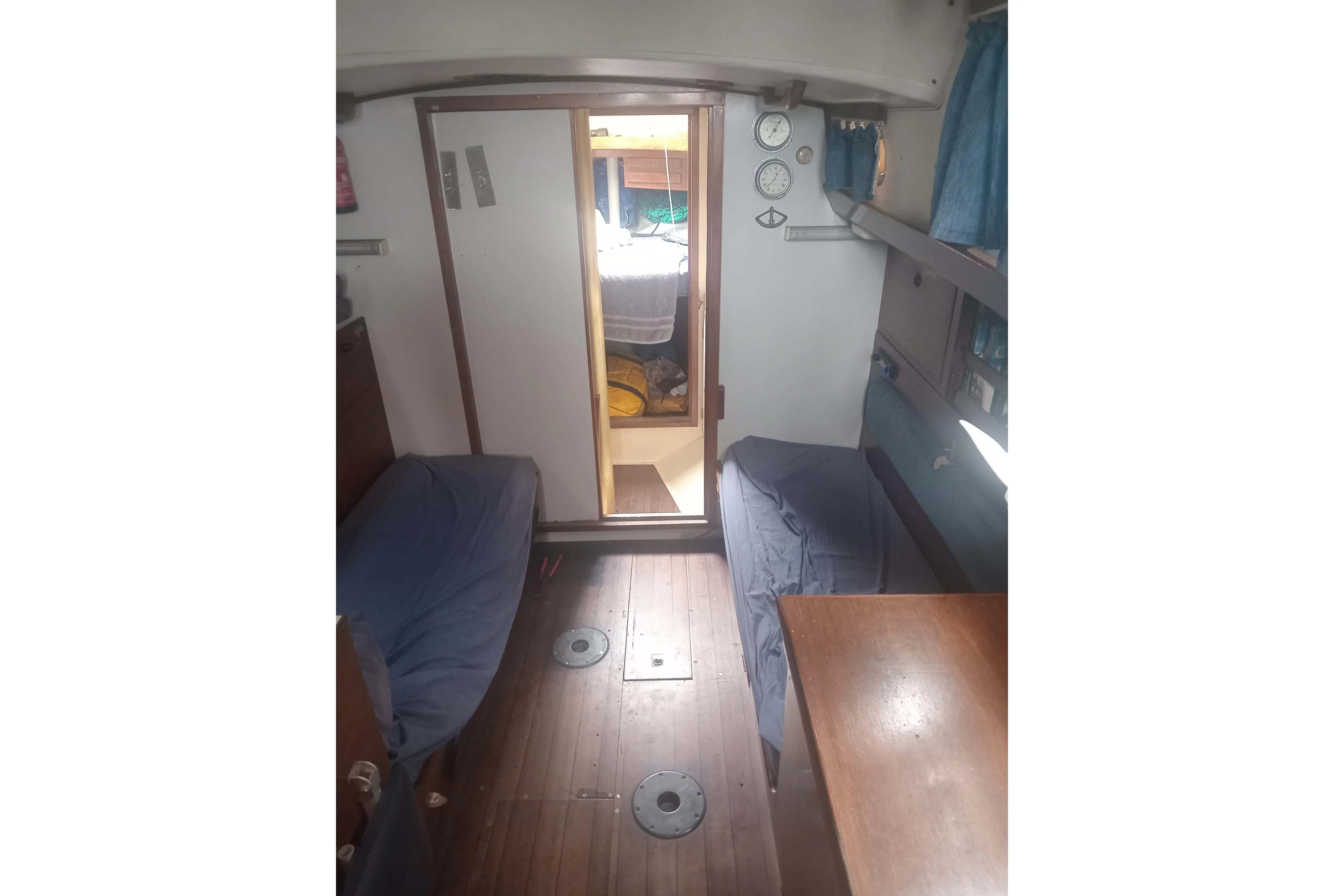 Interior of a 1965 Nicholson 32 sailboat with wooden flooring and cozy seating.