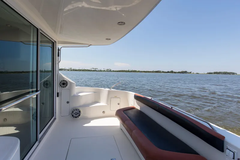 Silver Lining Yacht Photos Pics 2000 Sea Ray 400 Sedan Bridge yacht deck with seating, overlooking serene water and distant shoreline.