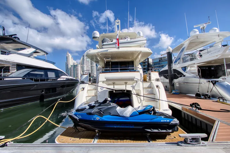 Julia Too Yacht Photos Pics Luxury 2002 Azimut 70 Sea Jet yacht docked with jet ski, city skyline in background.