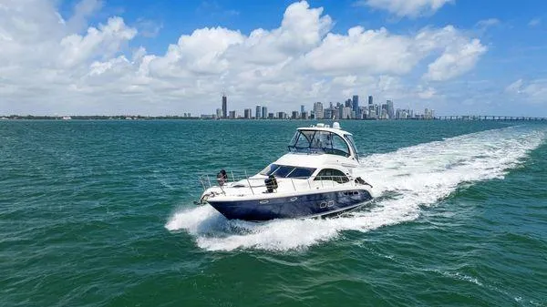  Yacht Photos Pics 2005 Sea Ray 52 Sedan Bridge cruising on open water with city skyline in background.