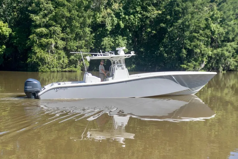  Yacht Photos Pics 2011 Yellowfin 36 Offshore boat cruising on a calm river with lush green trees.