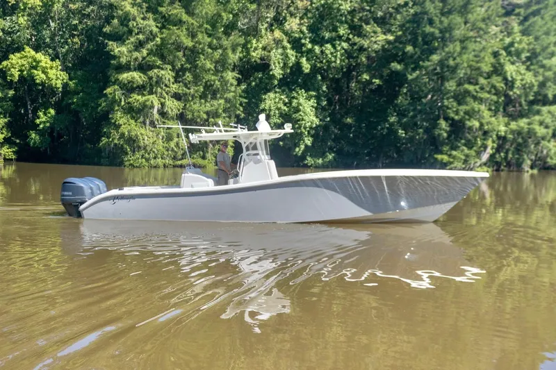  Yacht Photos Pics 2011 Yellowfin 36 Offshore boat cruising on a calm river surrounded by lush greenery.