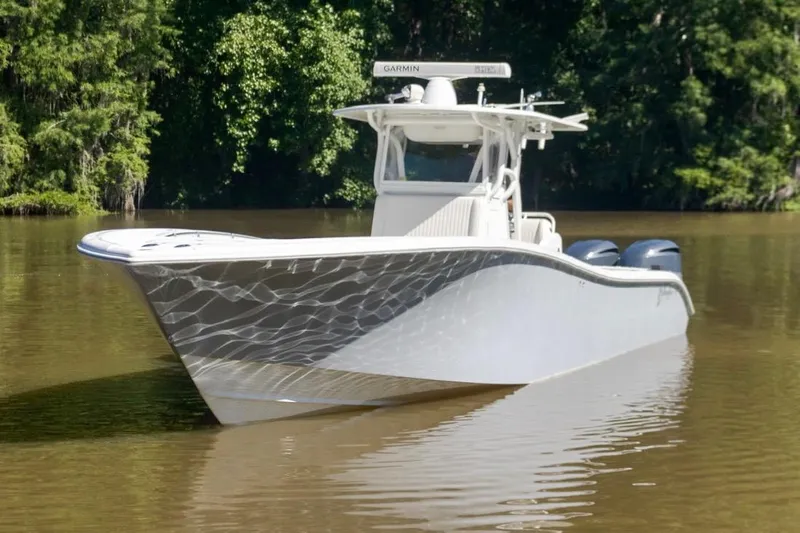  Yacht Photos Pics 2011 Yellowfin 36 Offshore boat on calm water, surrounded by lush greenery.