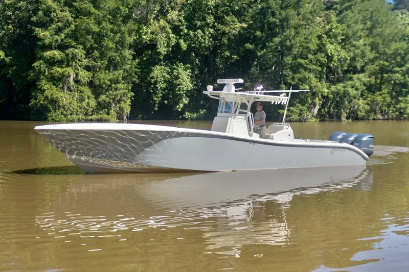  Yacht Photos Pics 2011 Yellowfin 36 Offshore boat cruising on a calm river with lush green trees.