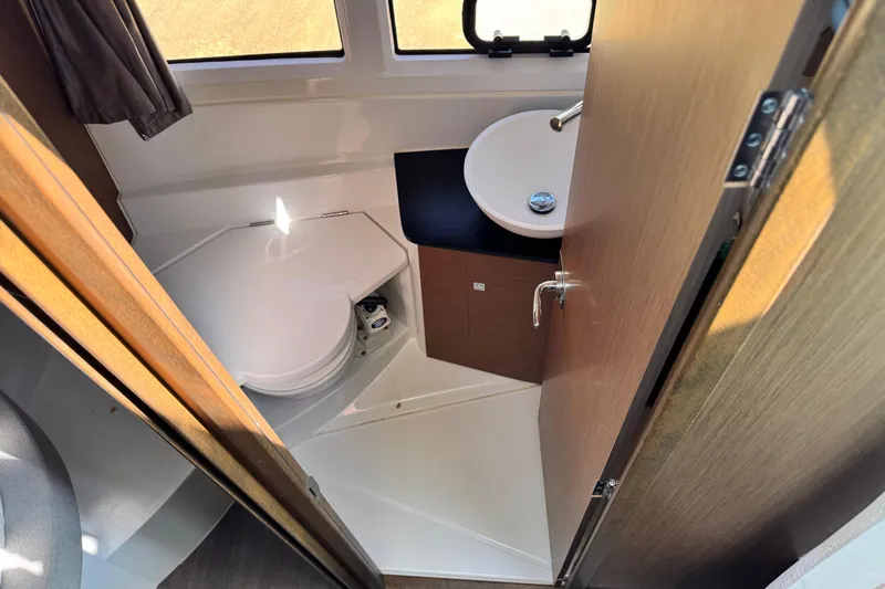  Yacht Photos Pics Compact bathroom in 2019 Jeanneau NC 895 boat, featuring toilet and sink.