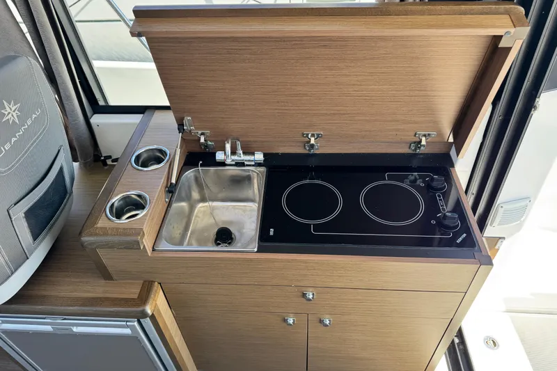  Yacht Photos Pics 2019 Jeanneau NC 895 boat kitchen with sink and dual-burner stove.
