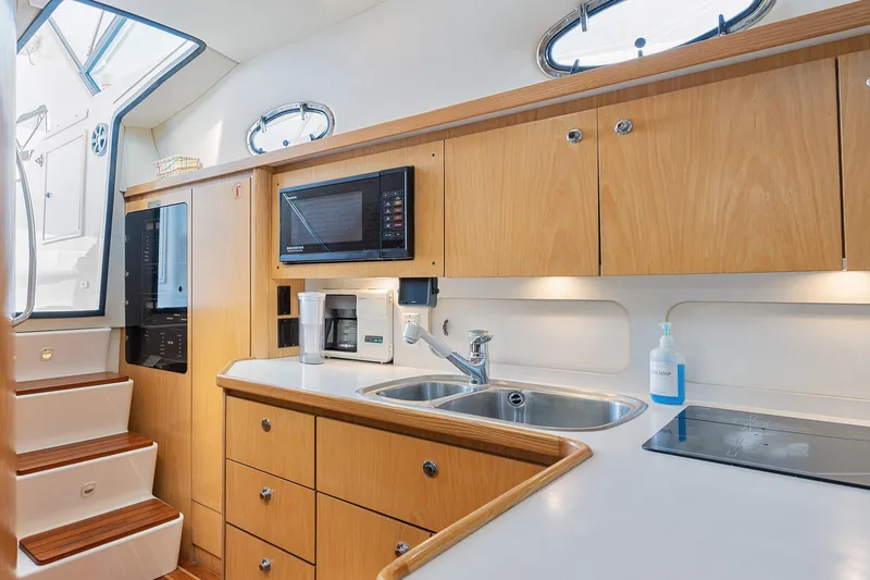  Yacht Photos Pics 1999 Tiara Yachts 4000 Express kitchen with wooden cabinets, sink, microwave, and stairs.