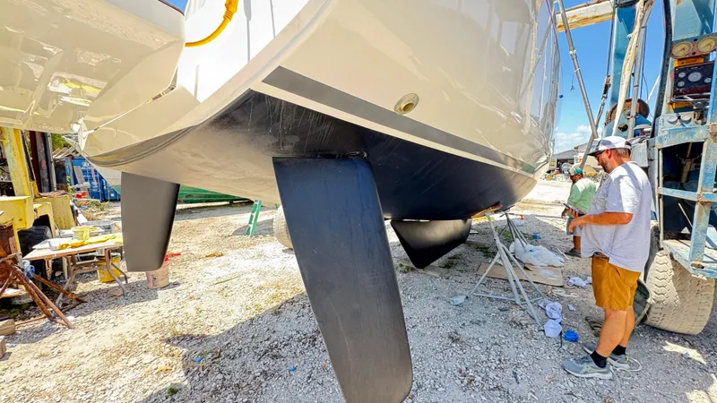  Yacht Photos Pics 2023 Beneteau Oceanis 34.1 sailboat in dry dock, with a person inspecting the hull.