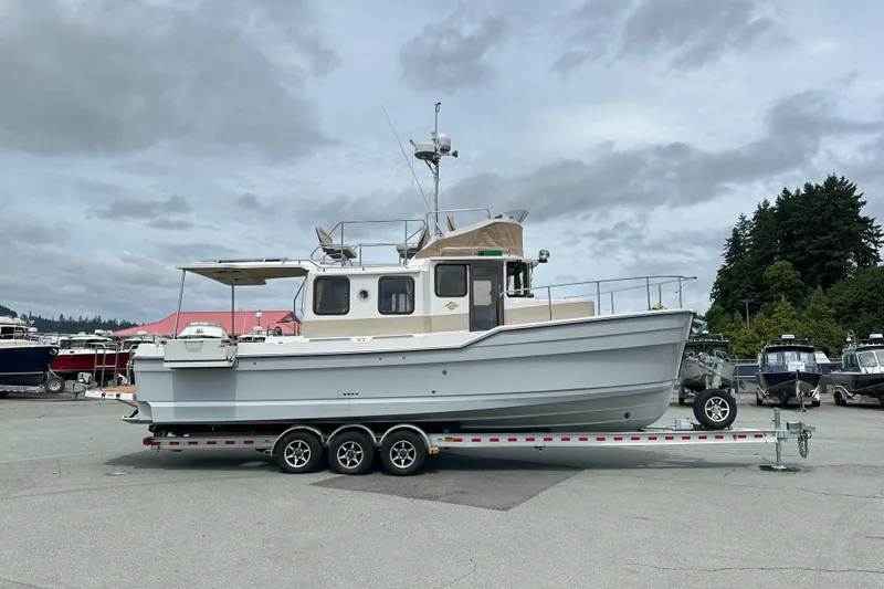  Yacht Photos Pics 2025 Ranger Tugs R-31 CB boat on trailer, parked outdoors under cloudy sky.