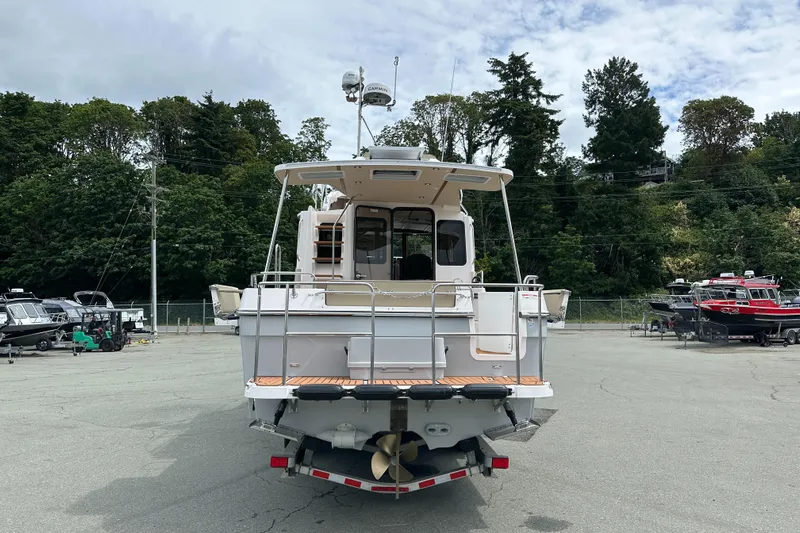  Yacht Photos Pics 2025 Ranger Tugs R-31 CB boat, rear view, parked on a lot with trees in background.
