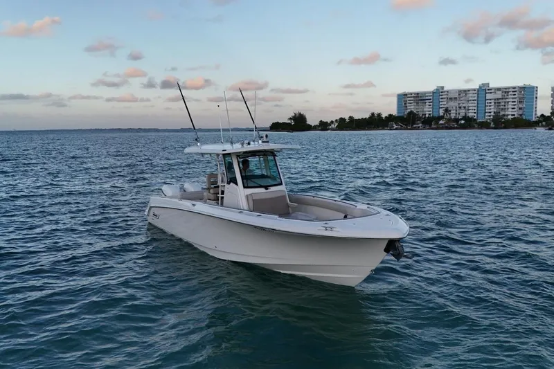  Yacht Photos Pics 2017 Boston Whaler 330 Outrage boat on calm ocean near coastal buildings.