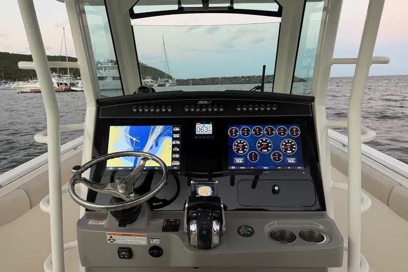  Yacht Photos Pics 2017 Boston Whaler 330 Outrage helm with navigation screens and steering wheel, docked by the sea.