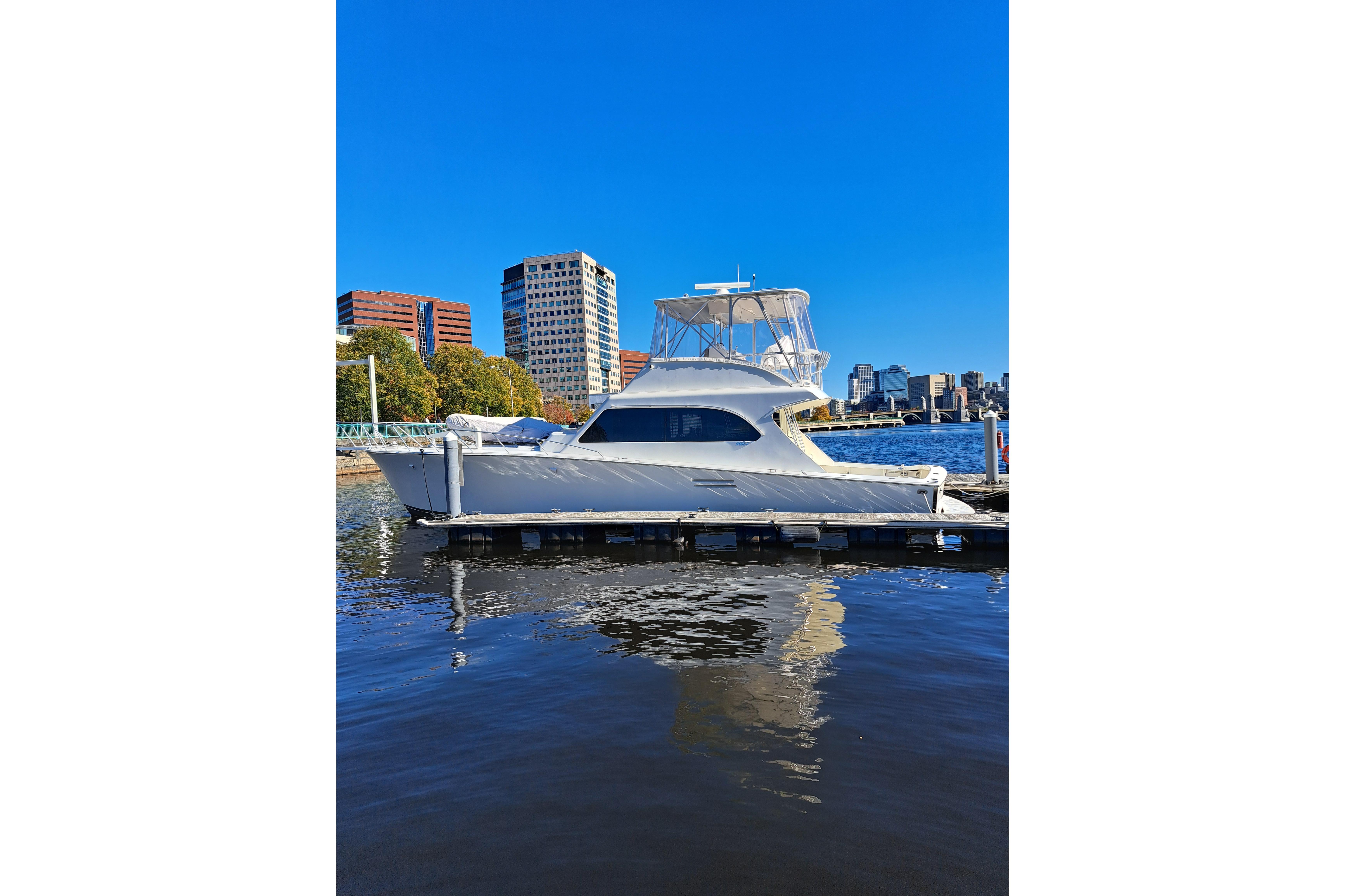 White 1995 Post 50 Convertible yacht docked in urban marina with city skyline backdrop.