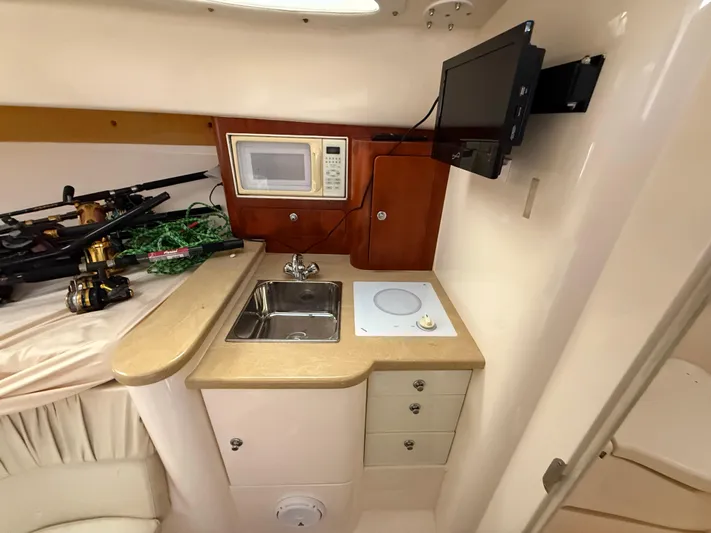  Yacht Photos Pics Compact kitchen area in a 2006 Intrepid 350 Center Console boat with sink, microwave, and TV.