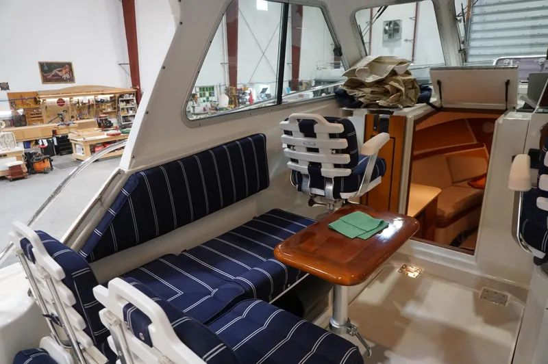 Halcyon Yacht Photos Pics 2006 Back Cove 29 boat interior with striped seating and wooden table in a workshop setting.
