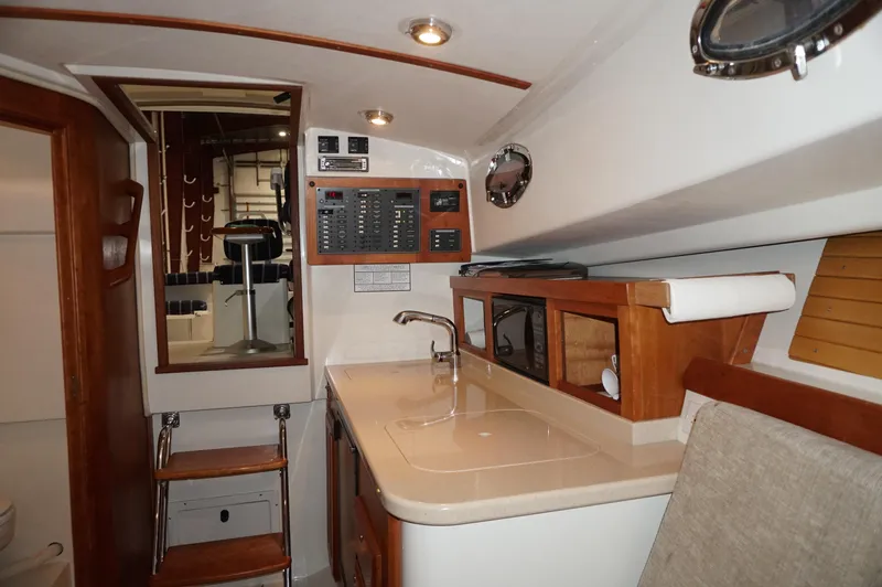 Halcyon Yacht Photos Pics 2006 Back Cove 29 yacht interior with kitchenette, control panel, and wooden cabinetry.